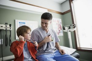 Male nurse and boy using stethoscope