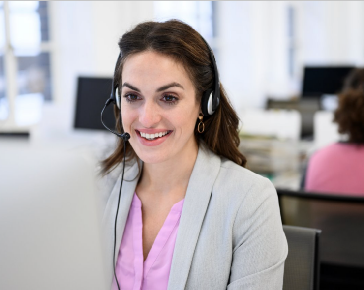 Businesswoman in her 30s seated at a desktop PC talking on a headset