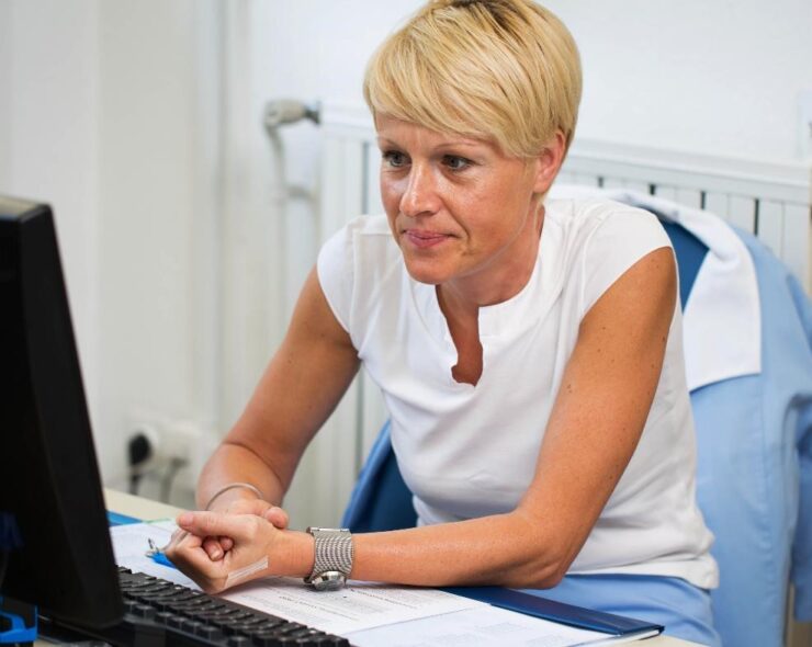 Female gp with short blonde hair looking at her computer