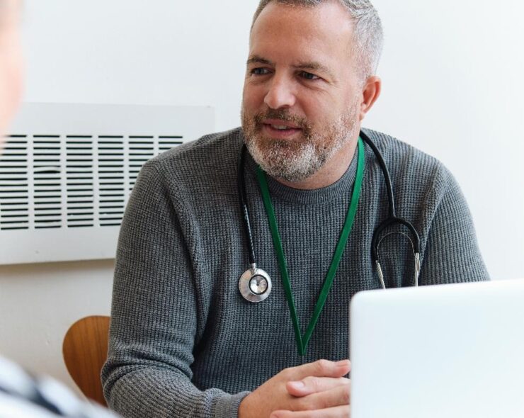 Healthcare Professional sitting in front of a laptop consulting with a patient