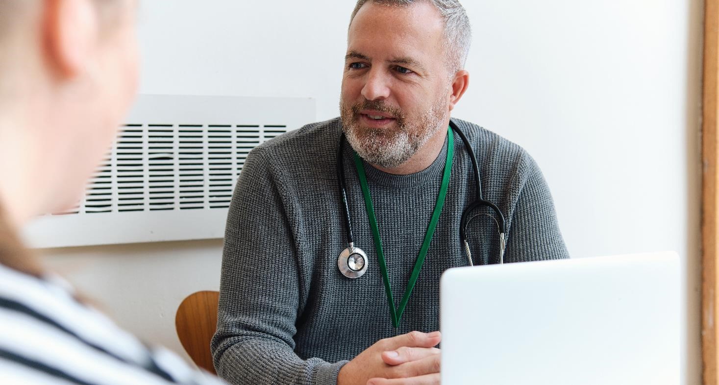 Healthcare Professional sitting in front of a laptop consulting with a patient