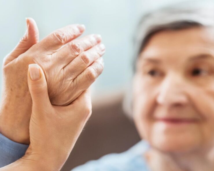 A close-up of a physician holding the hand of an arthritis patient