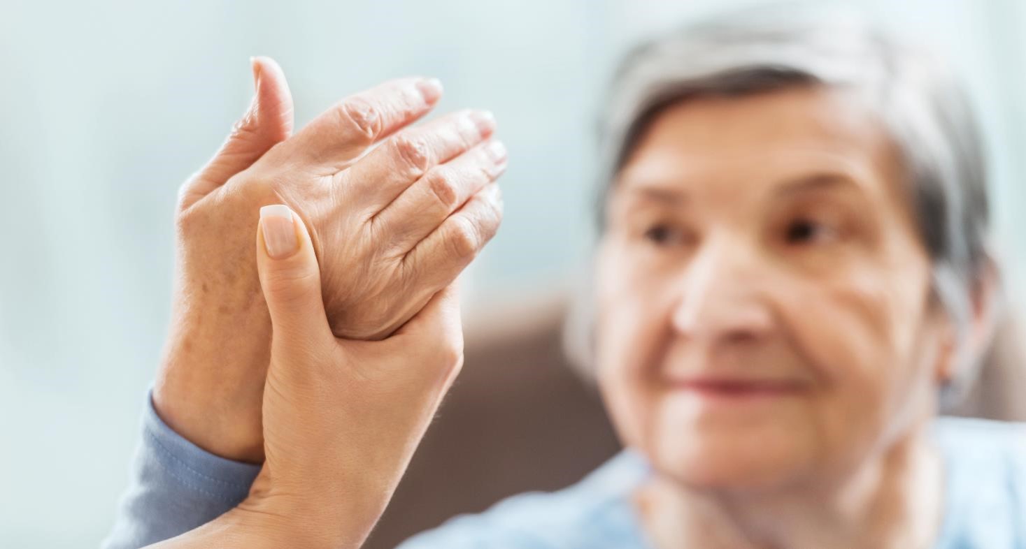 A close-up of a physician holding the hand of an arthritis patient